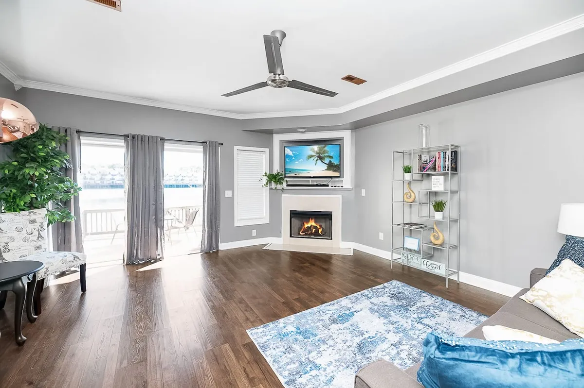 A stylish, modern living room anchored by a comfortable sofa and a fireplace, with expansive windows bringing in natural light and offering serene views. The space feels both cozy and contemporary, ideal for entertaining or quiet relaxation.